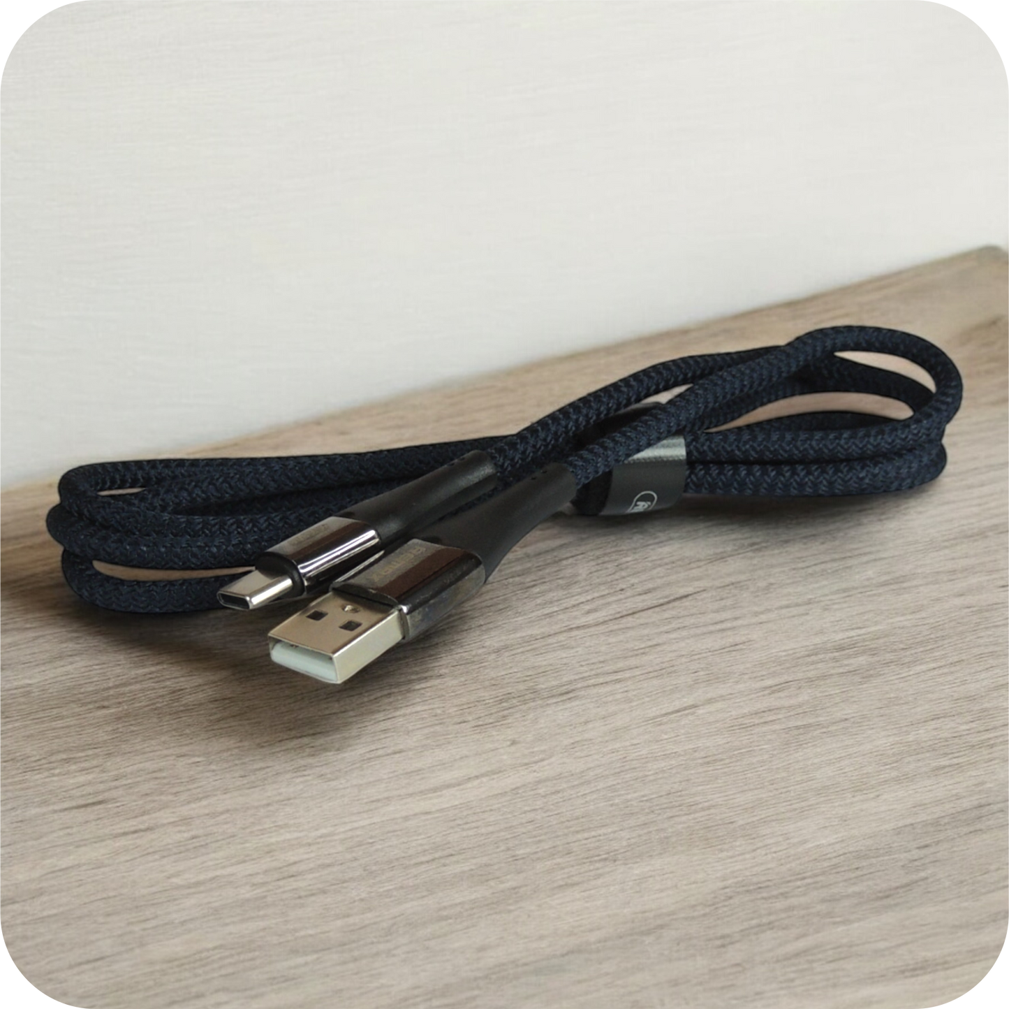 cable usb negro de material trenzado enrollado sobre superficie de madera