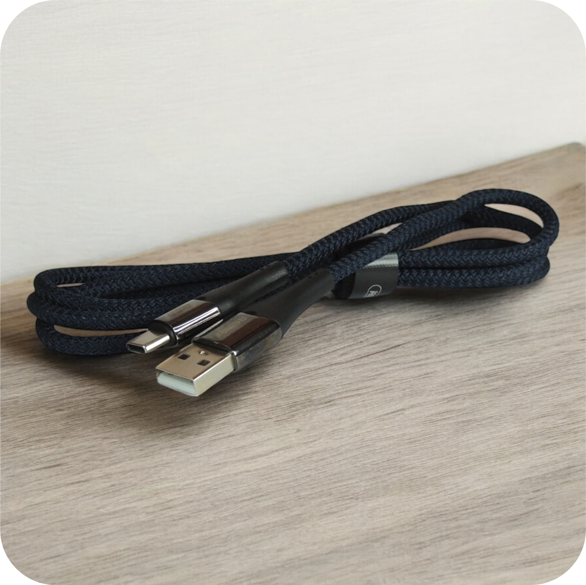 cable usb negro de material trenzado enrollado sobre superficie de madera