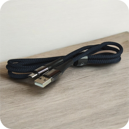 cable usb negro de material trenzado enrollado sobre superficie de madera