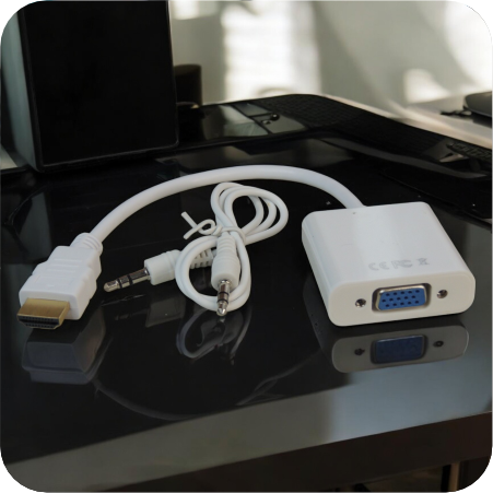 convertidor hdmi a vga y cable de audio blancos en espacio de trabajo